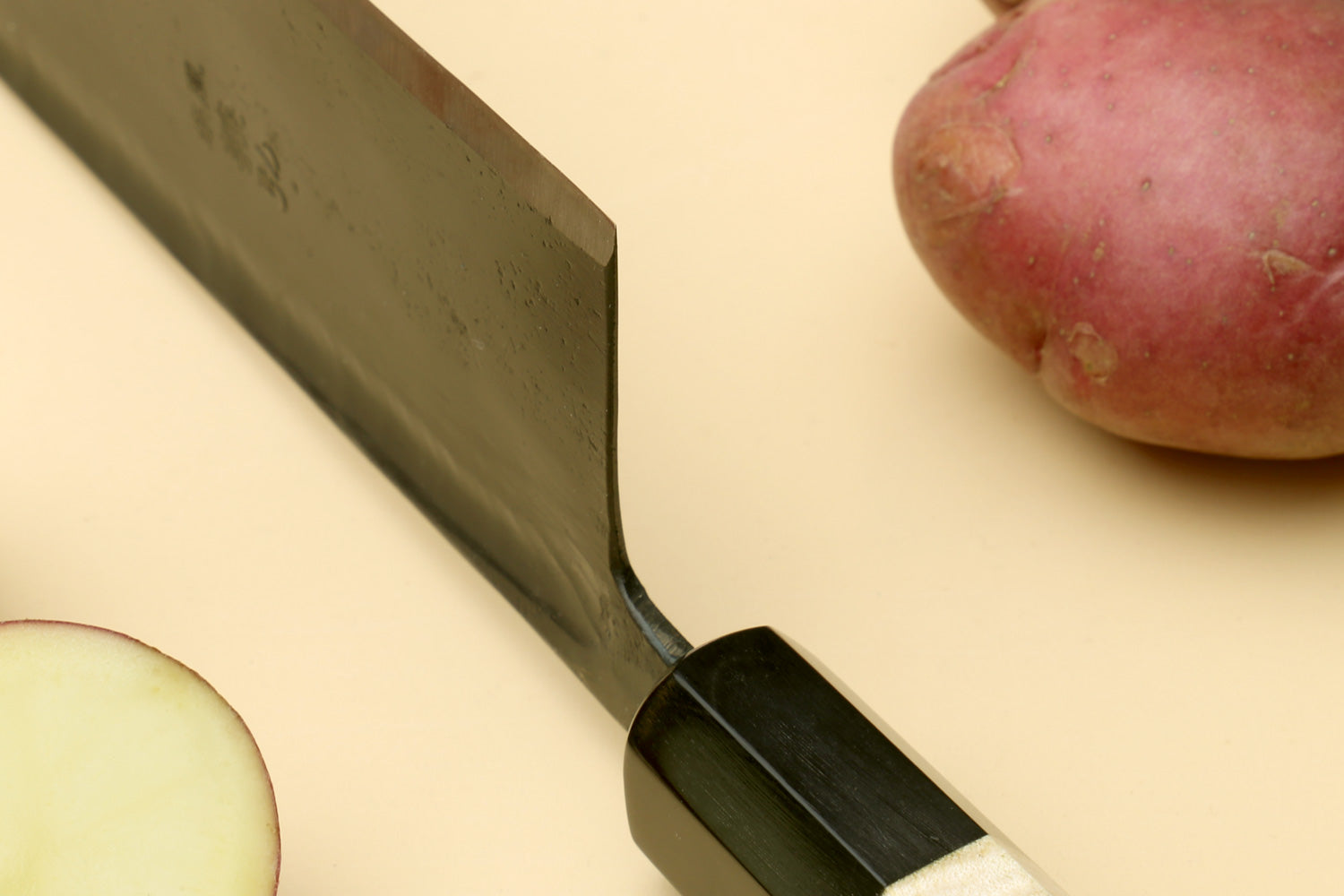 Nakiri vegetable knife tip and bolster: dark steel blade on black handle ferrule