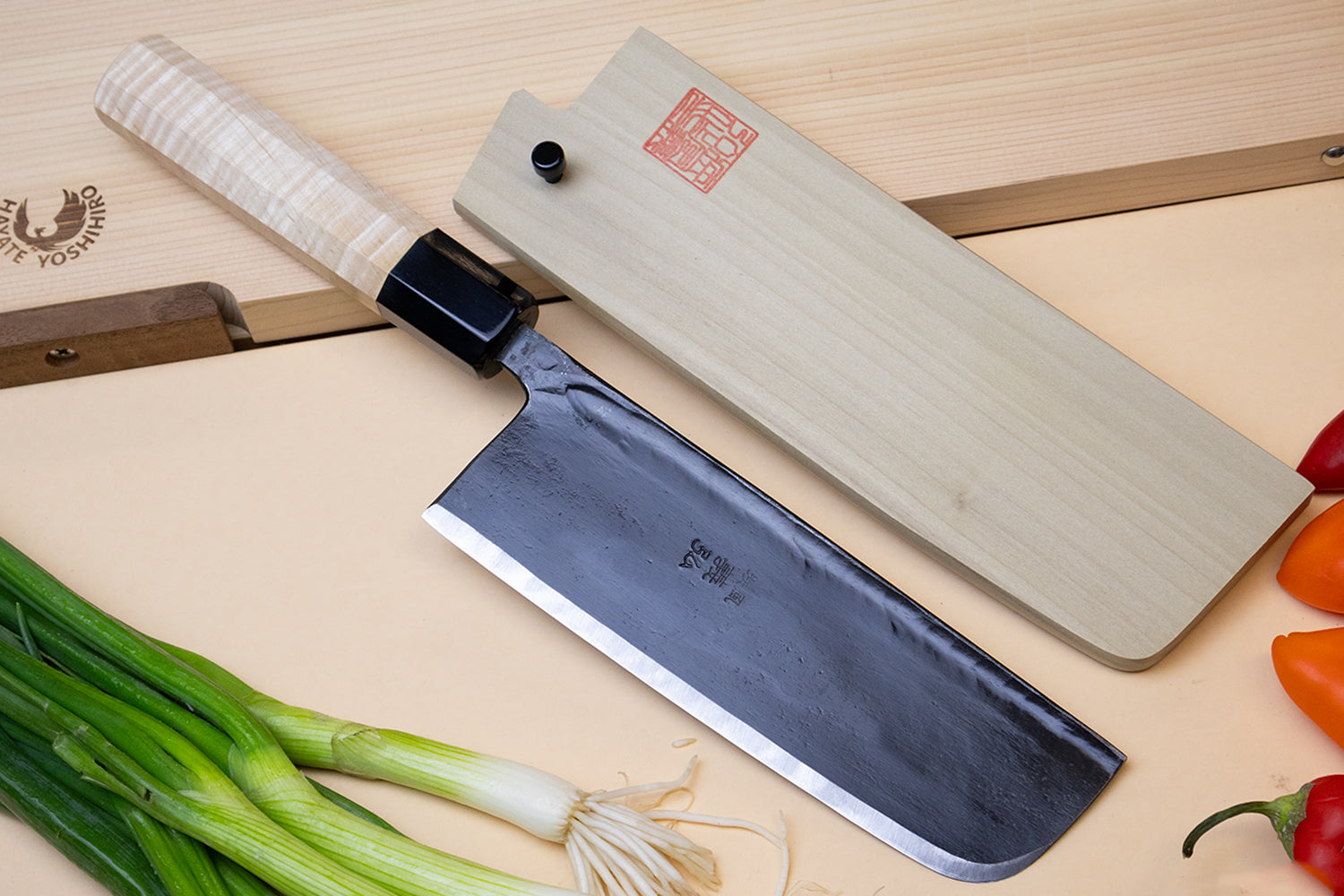 Nakiri vegetable knife with dark blade and light camphor handle, in wooden saya cover