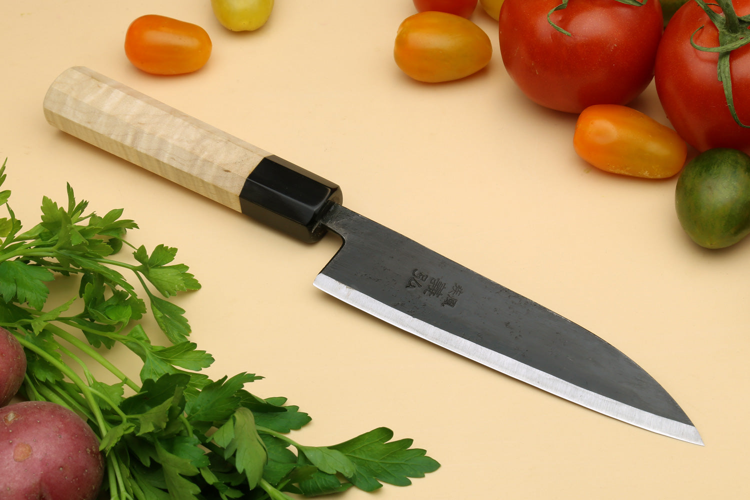 Petty utility Japanese knife with pale camphor handle and dark blade guard, pointed edge