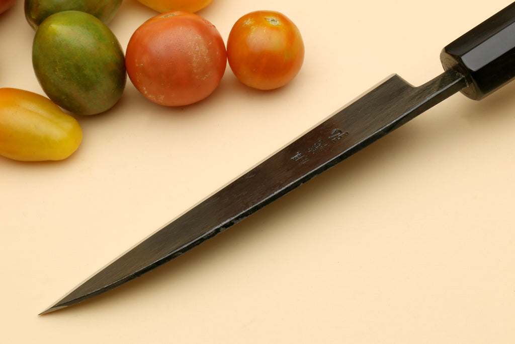 Petty utility Japanese knife with dark collar and pointed blade, angled view