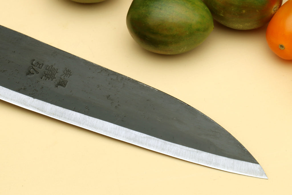 Petty utility Japanese knife blade close-up with etched marks and pale edge reflection