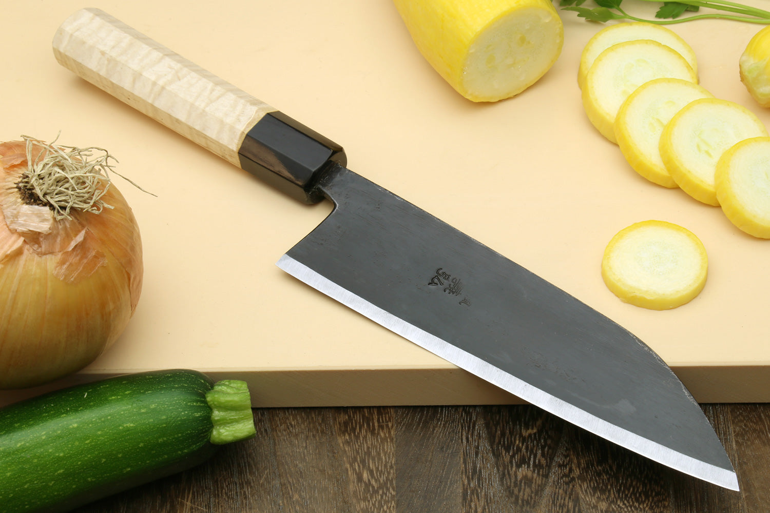 Santoku chef knife with dark blade and light camphor handle, cutting edge close-up