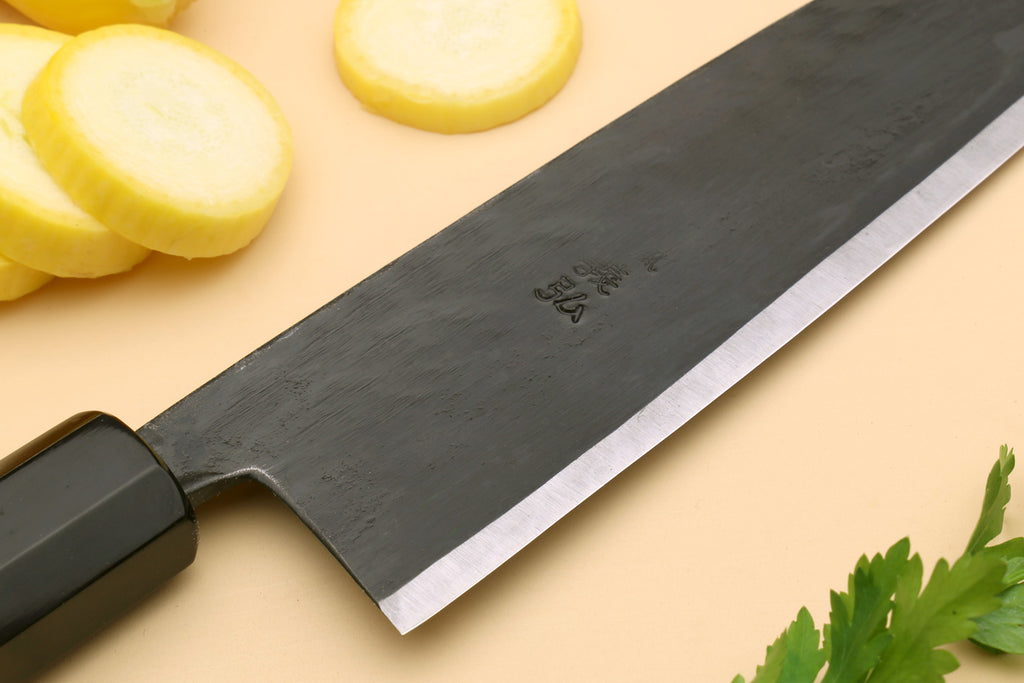 Santoku chef knife close-up of blade face with stamped marking and dark steel