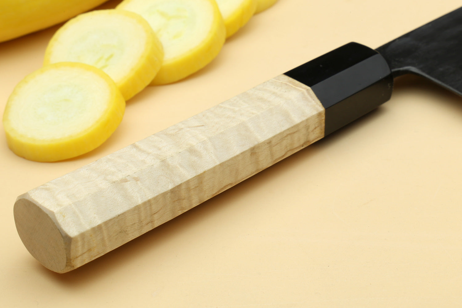 Santoku chef knife with light camphor handle, black bolster, blade at angle