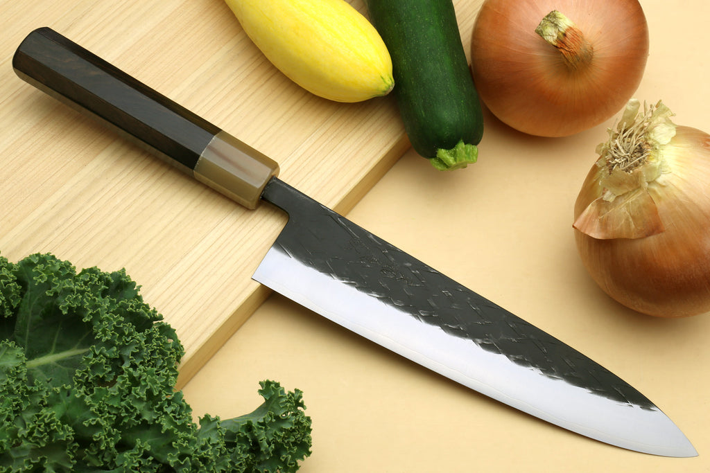 Gyuto chef's knife with dark handle and black-speckled blade, stainless edge