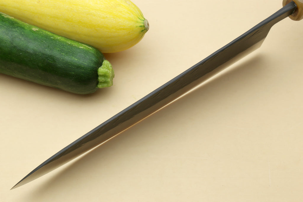 Gyuto chef's knife angled with dark handle and black-patterned blade