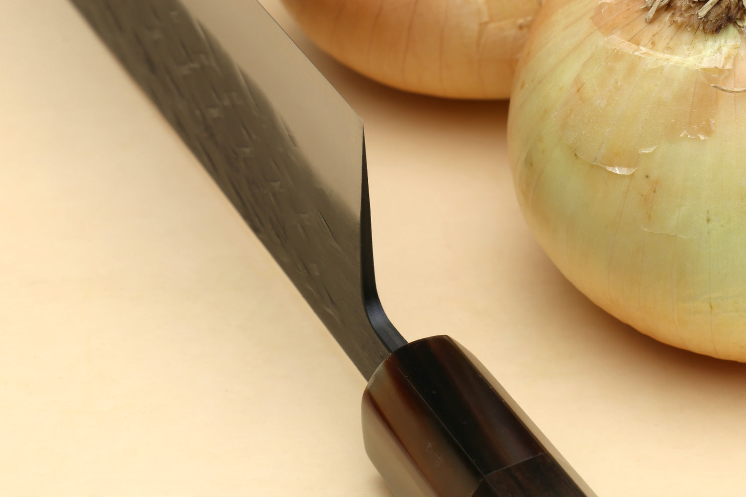 Nakiri vegetable knife with dark pointed blade tip and curved cutting edge, black handle