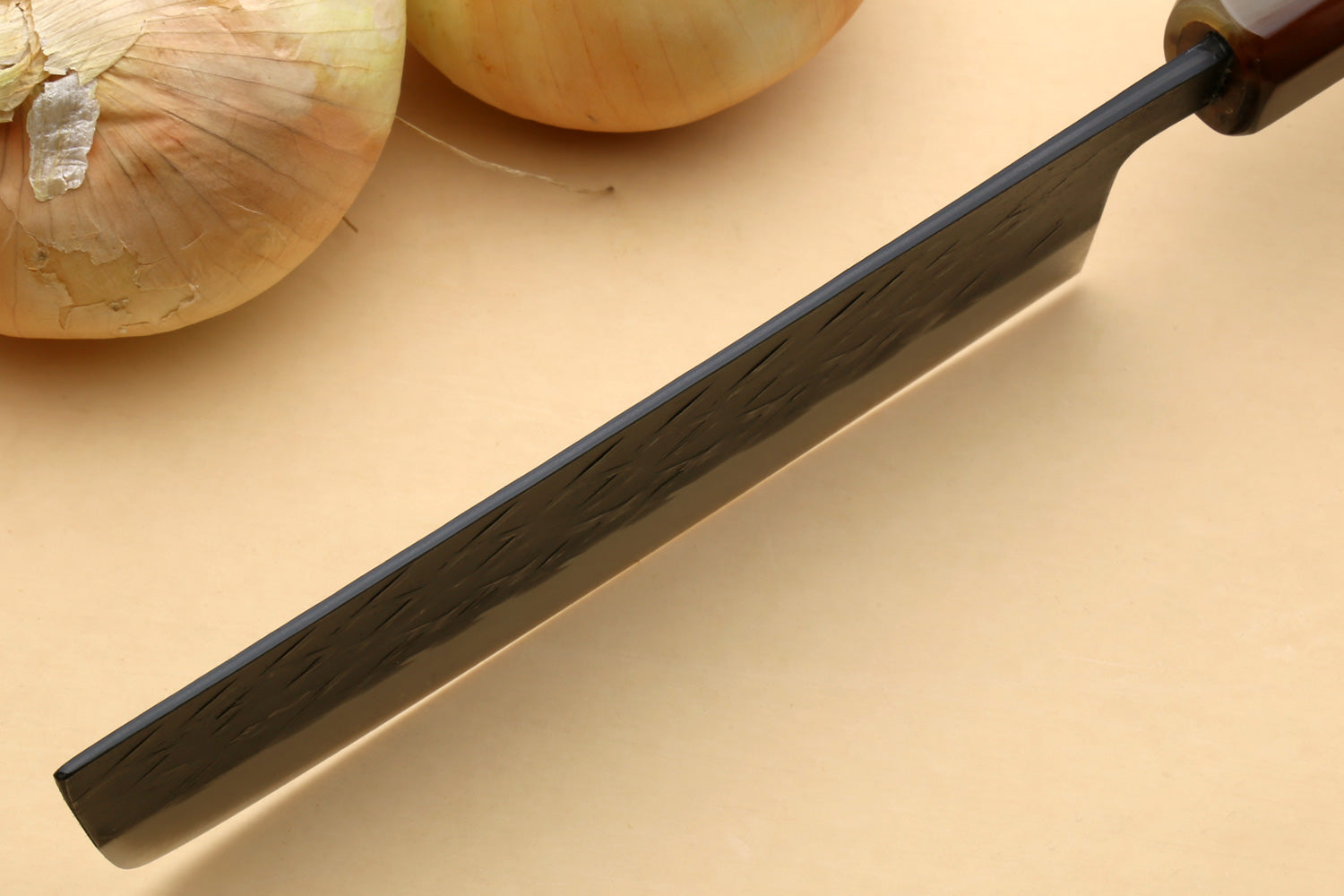 Nakiri vegetable knife with long dark hammered blade and black-tinted bolster, handle view