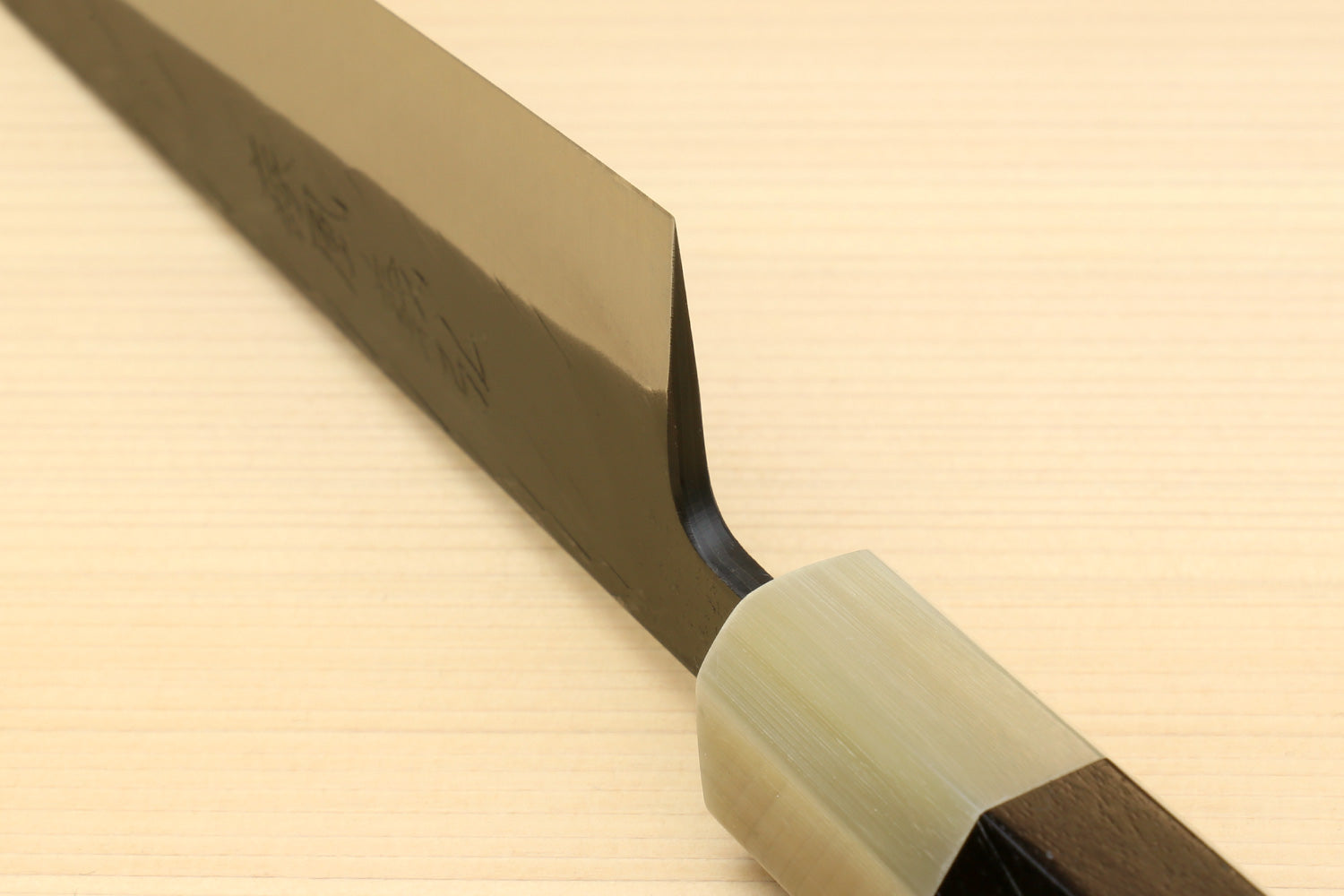 Petty-utility knife side view with dark blade and light handle with brass-colored ferrule