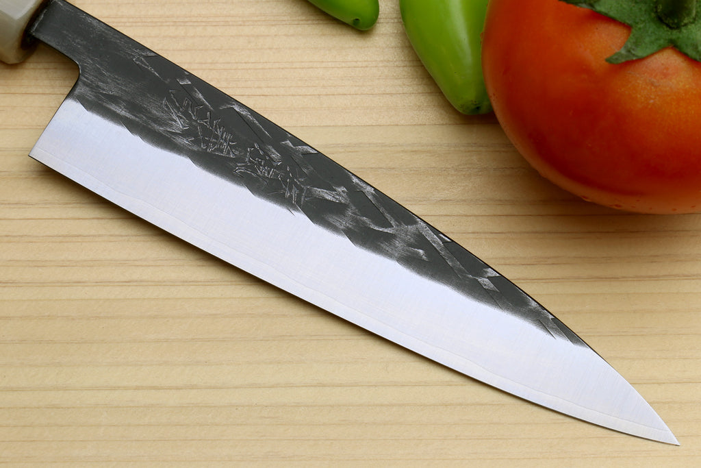 Petty utility knife close view of long gray patterned blade and cutting edge