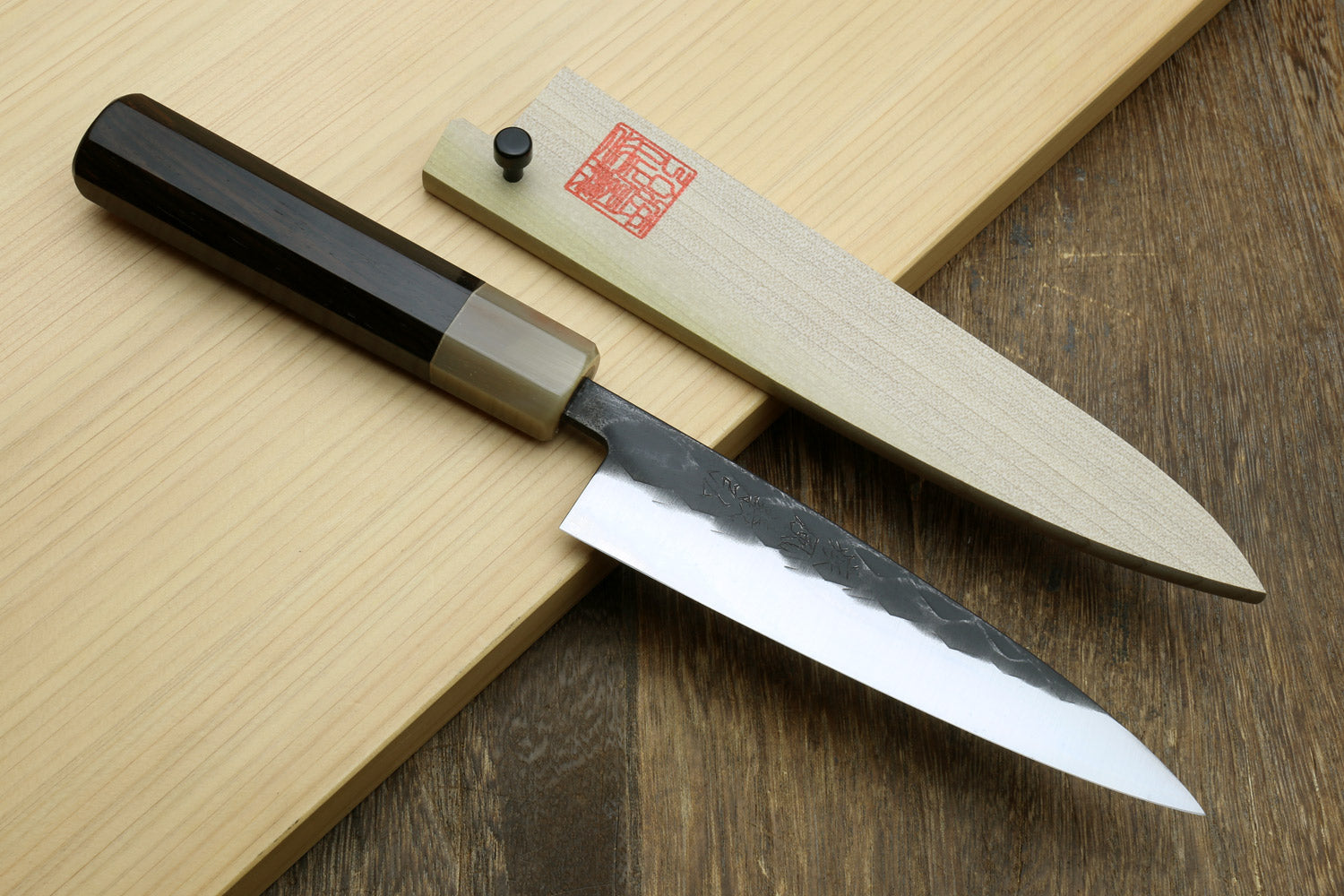 Santoku and petty knives with dark handles and hammered-texture steel blades