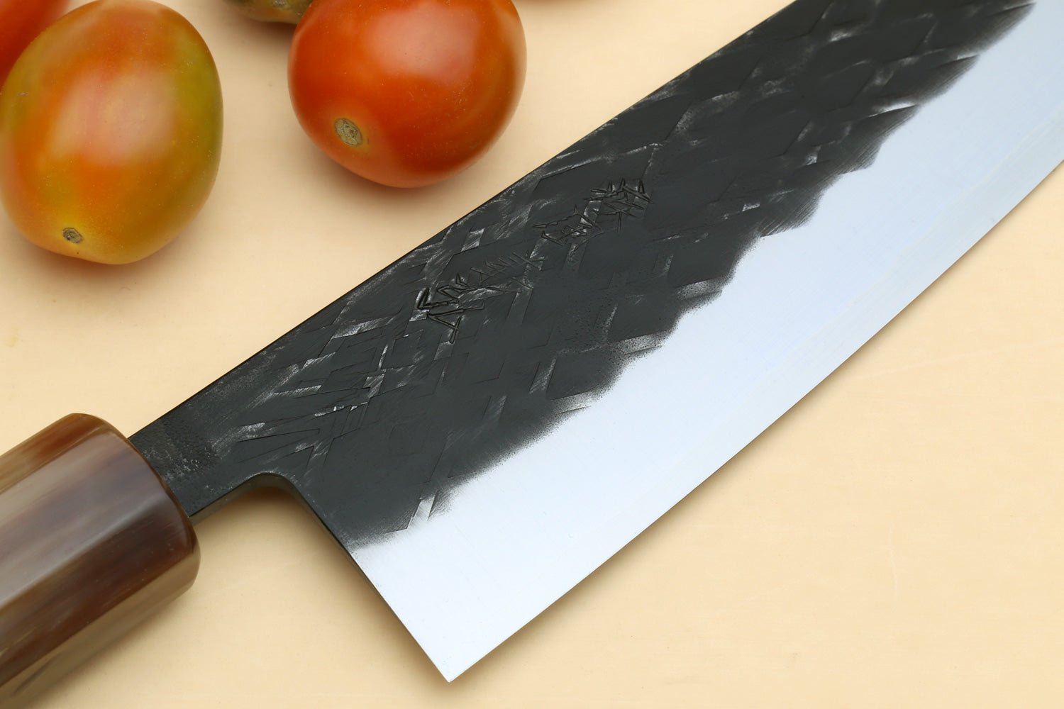 Santoku knife blade with hammered, faceted texture and dark spine