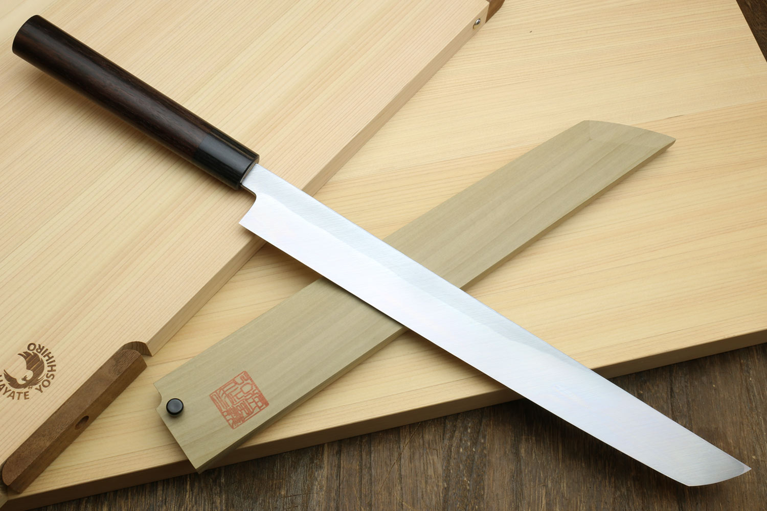 Japanese sushi sashimi knife with white steel sakimaru blade and dark wood handle on board