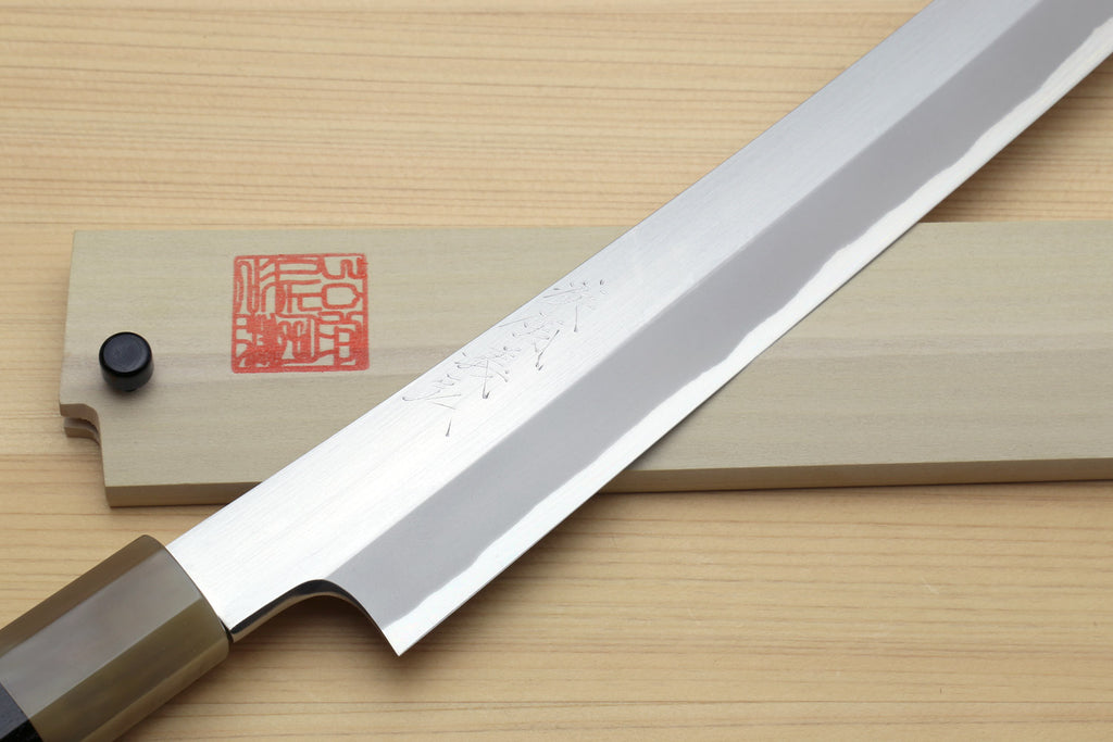 Sushi sashimi knife close-up: curved white blade with engraved marks and wood handle