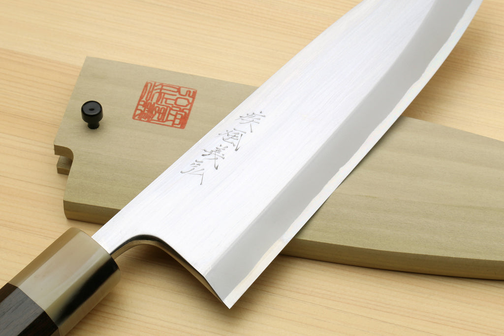 Deba knife close-up of white blade with etched markings and dark handle