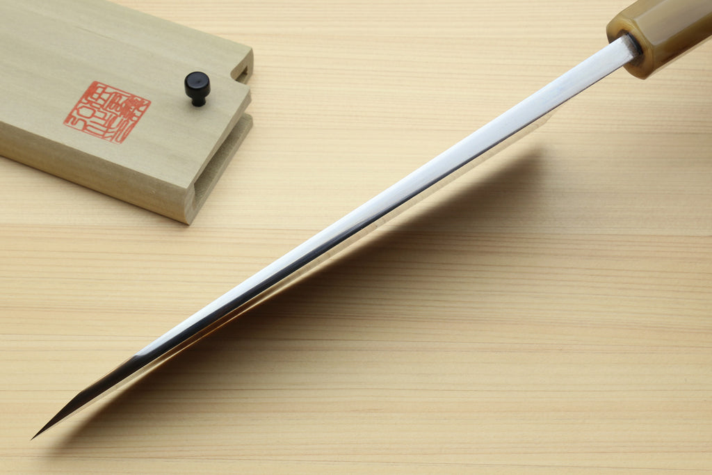 Deba knife with white blade and dark handle, tip pointing left