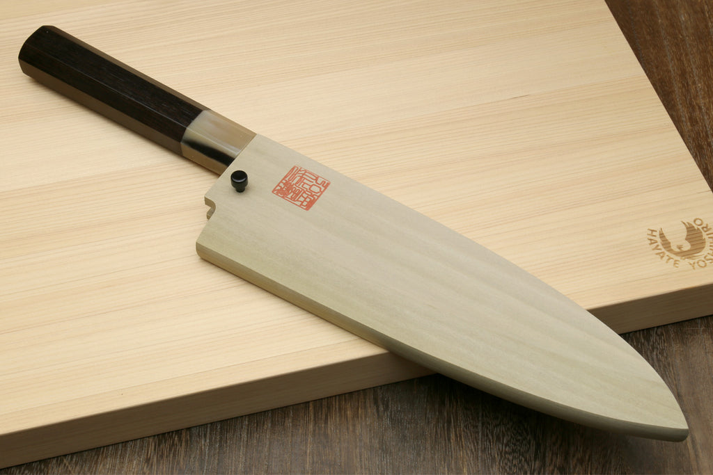 Deba chef knife on wooden board with white blade and ebony-style dark handle