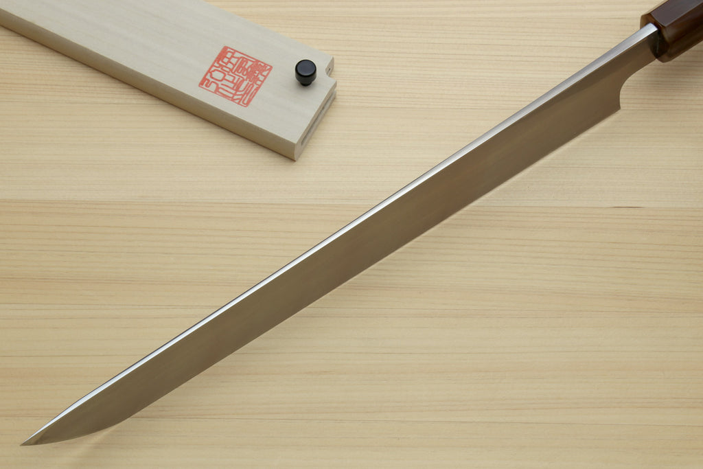 Sashimi sushi knife with long pointed white steel blade and dark handle on wood