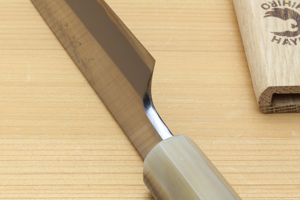 Yanagiba knife close-up of white steel blade and curved bolster near edge