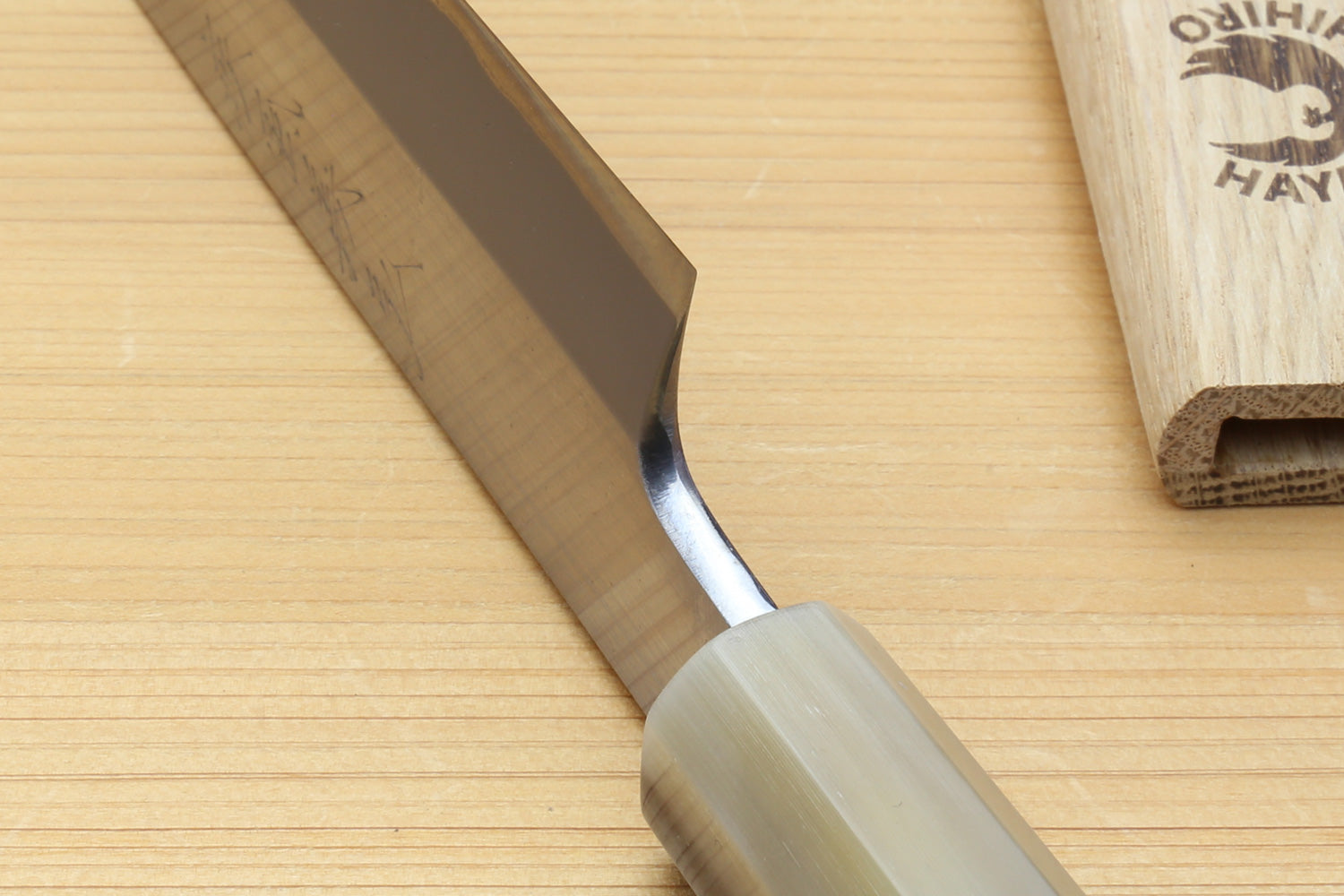 Yanagiba knife close-up of white steel blade and curved bolster near edge
