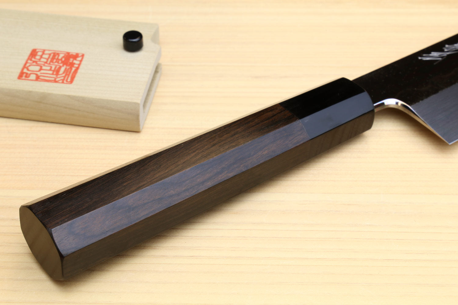 Japanese vegetable knife handle and heel detail with dark ebony grip on wood