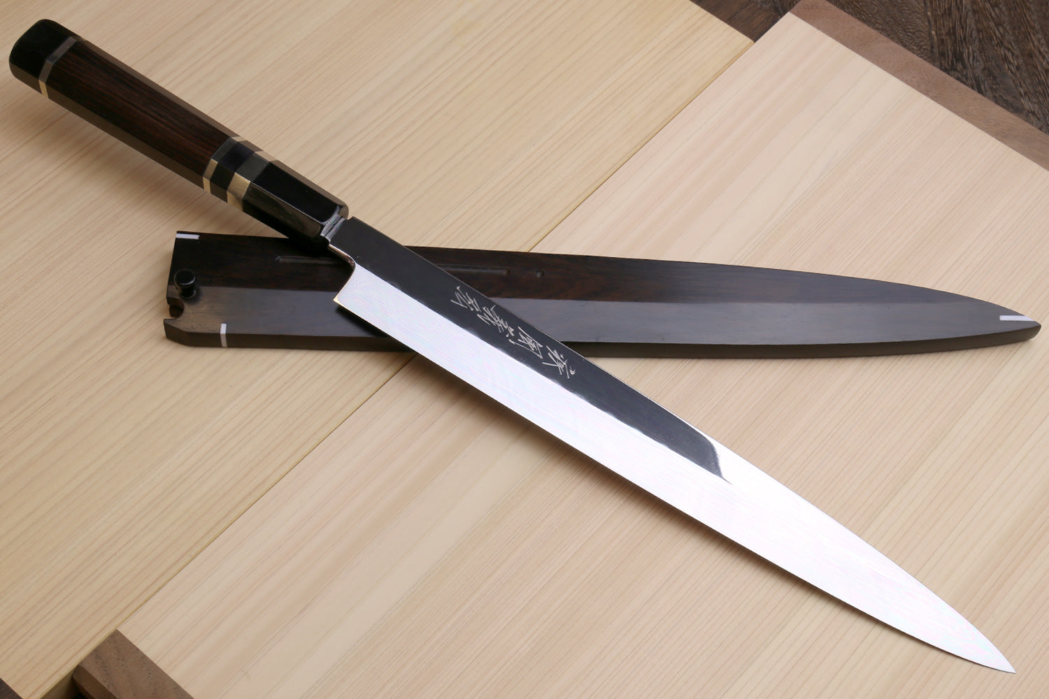 Mirror-finished steel Japanese-style knife with etched markings and dark handle, angled.