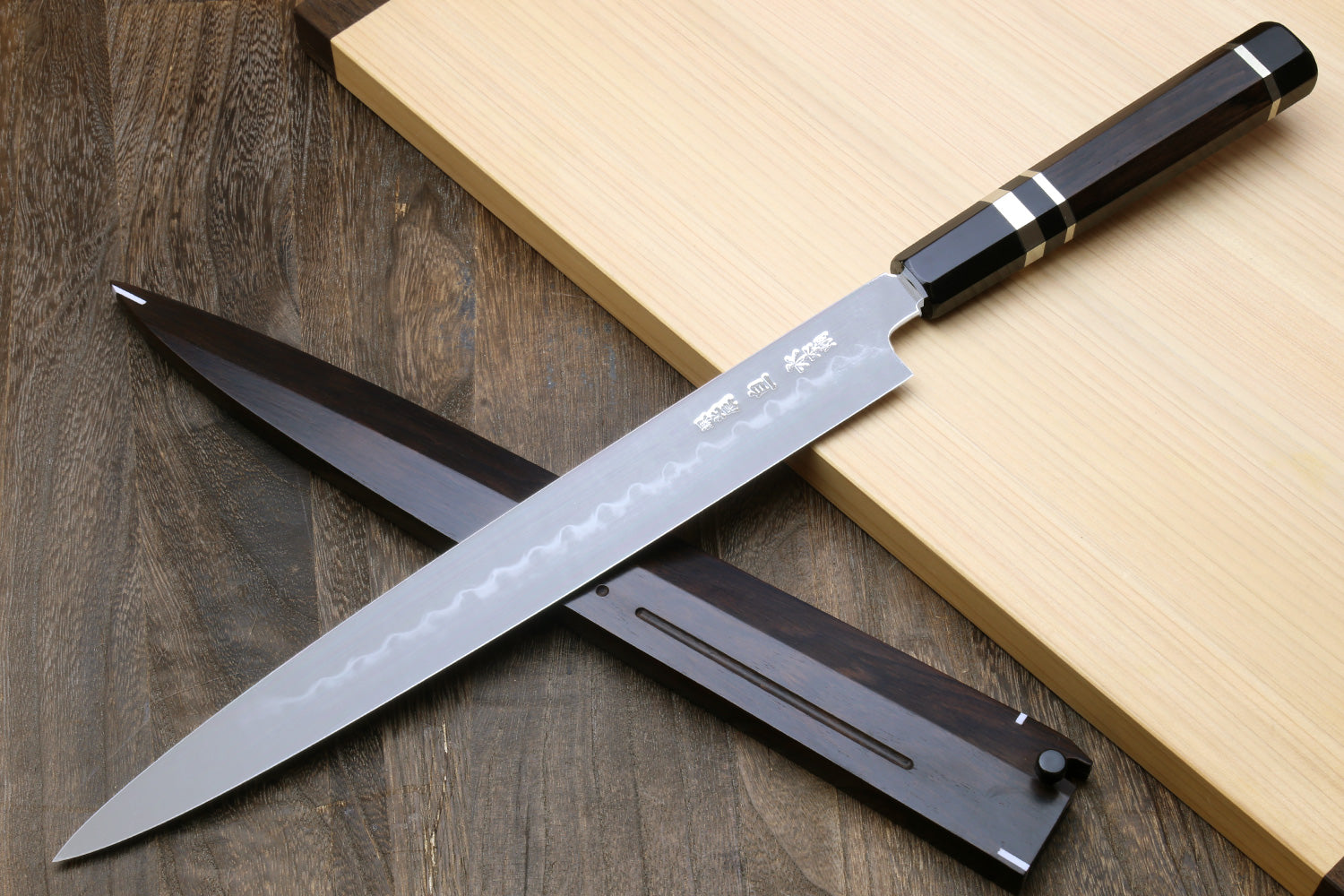 Mirror-finished steel knife blade with etched text and dark handle on black base.
