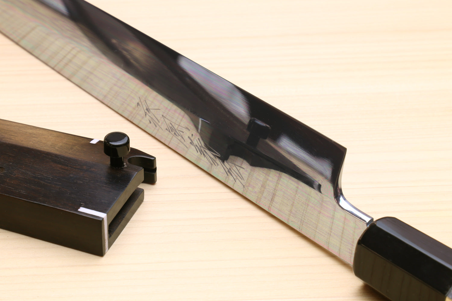 Steel knife with mirror finish and dark handle; blade guard and pommel visible.
