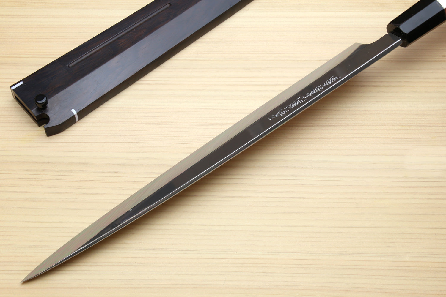 Mirror-finished steel knife with etched text and dark handle, full-length view.