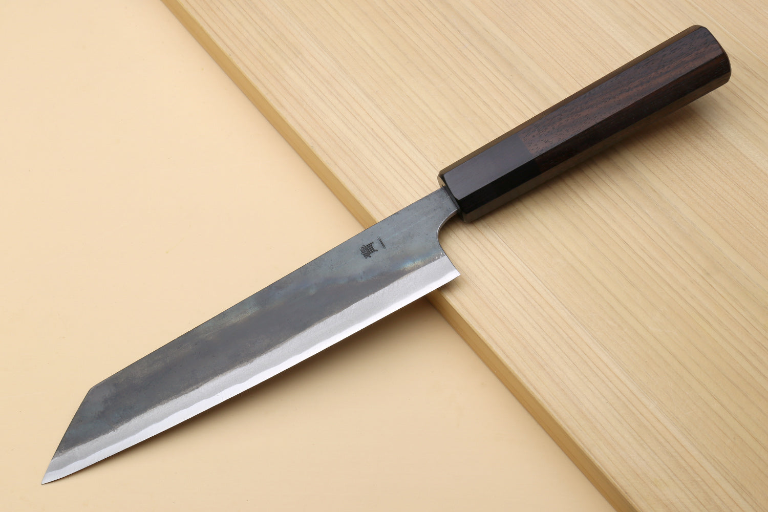 Japanese utility kiritsuke knife with dark handle and partially visible edge on steel blade