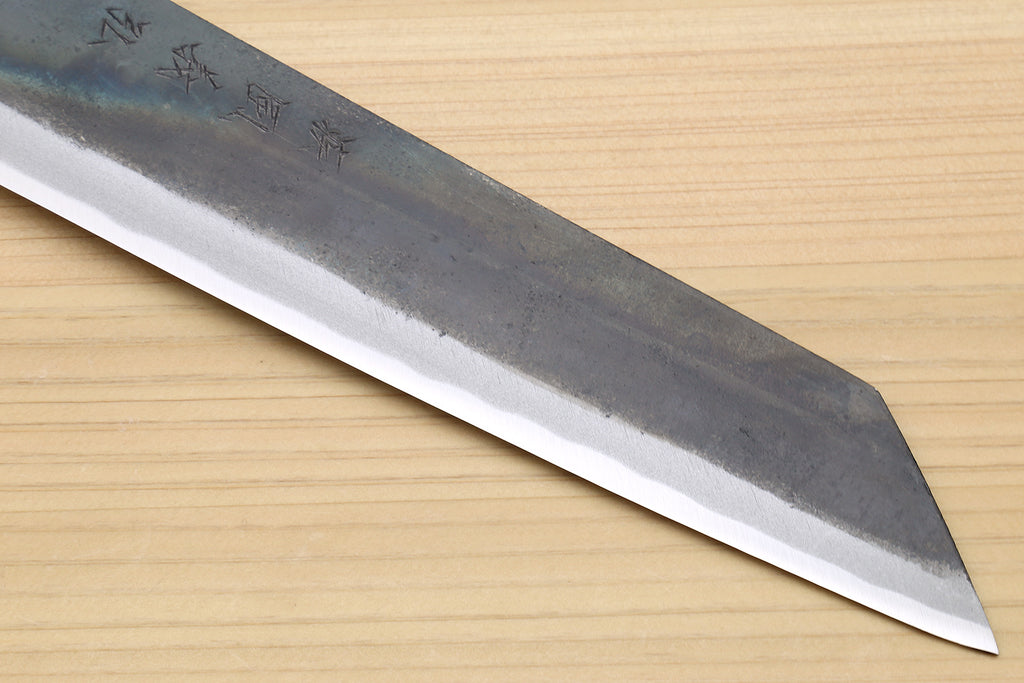 Japanese utility kiritsuke knife tip close-up with kurouchi-style steel blade and markings