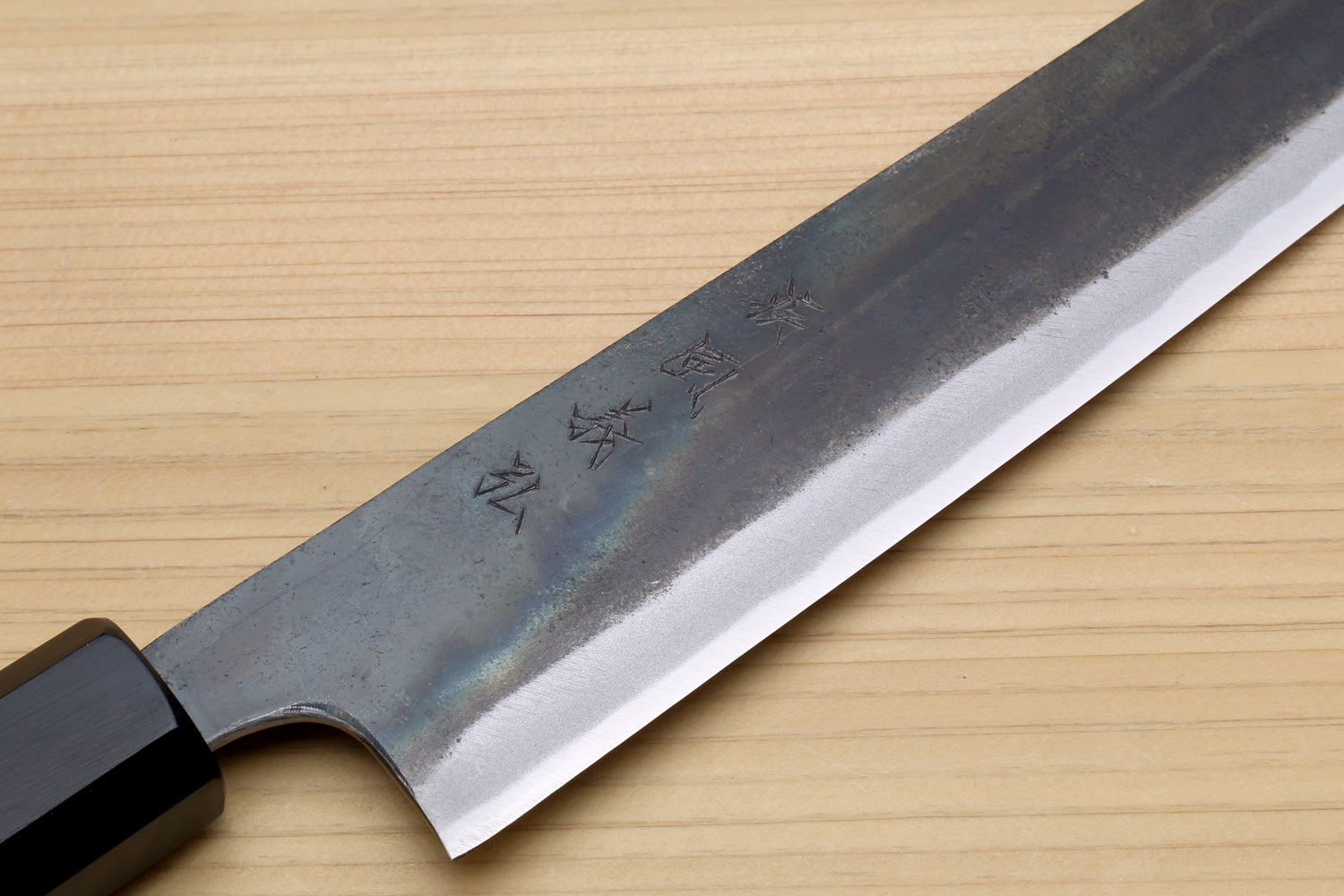 Japanese utility kiritsuke knife close-up of blade spine markings and dark wooden handle