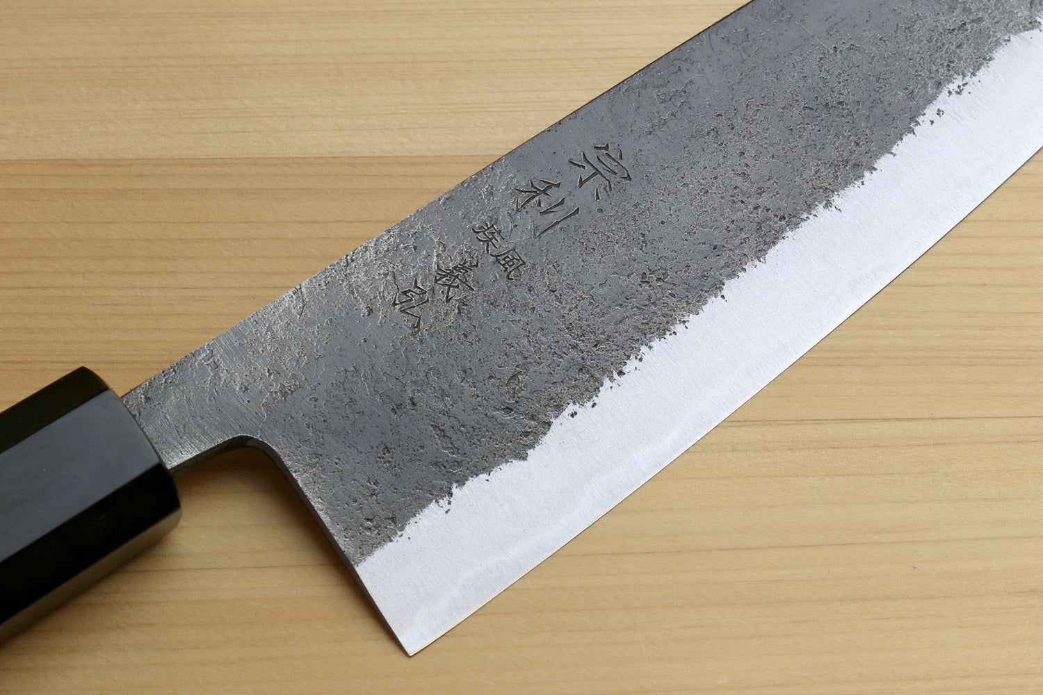 Japanese Bunka chef knife blade close-up with white edge and stamped markings