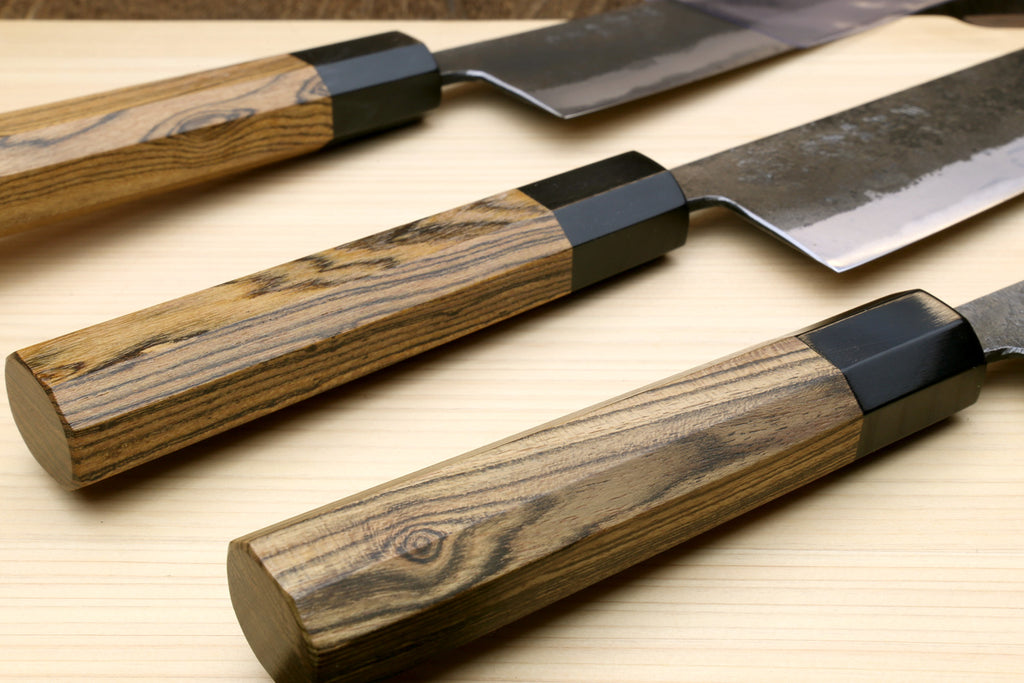 Japanese gyuto chef knife with dark cocobolo handle and white blade, black spine block