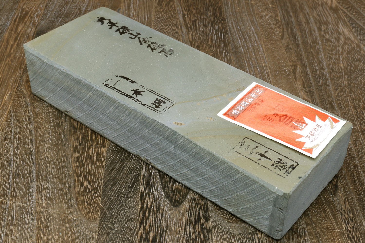 Natural sharpening whetstone in light paper wrap with orange label on side