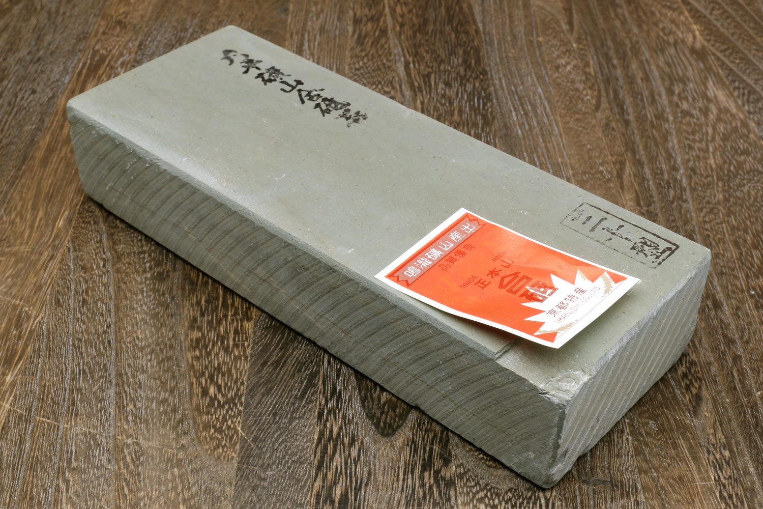 Sharpening whetstone with white face, dark sides, and orange sticker on top