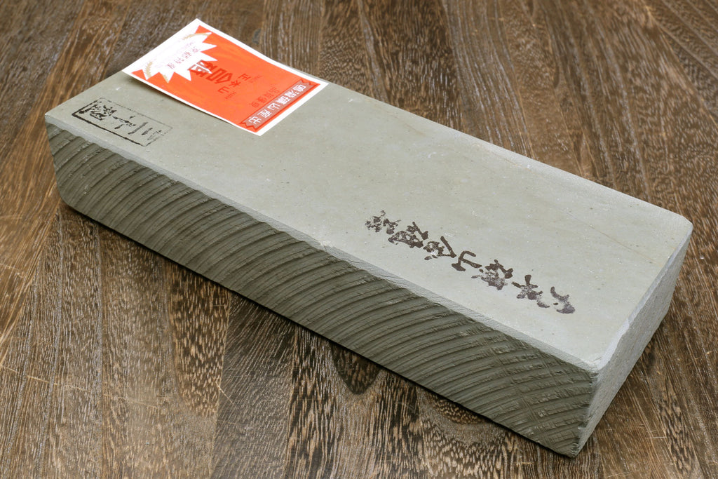 Sharpening whetstone with white face, dark textured sides, and orange label