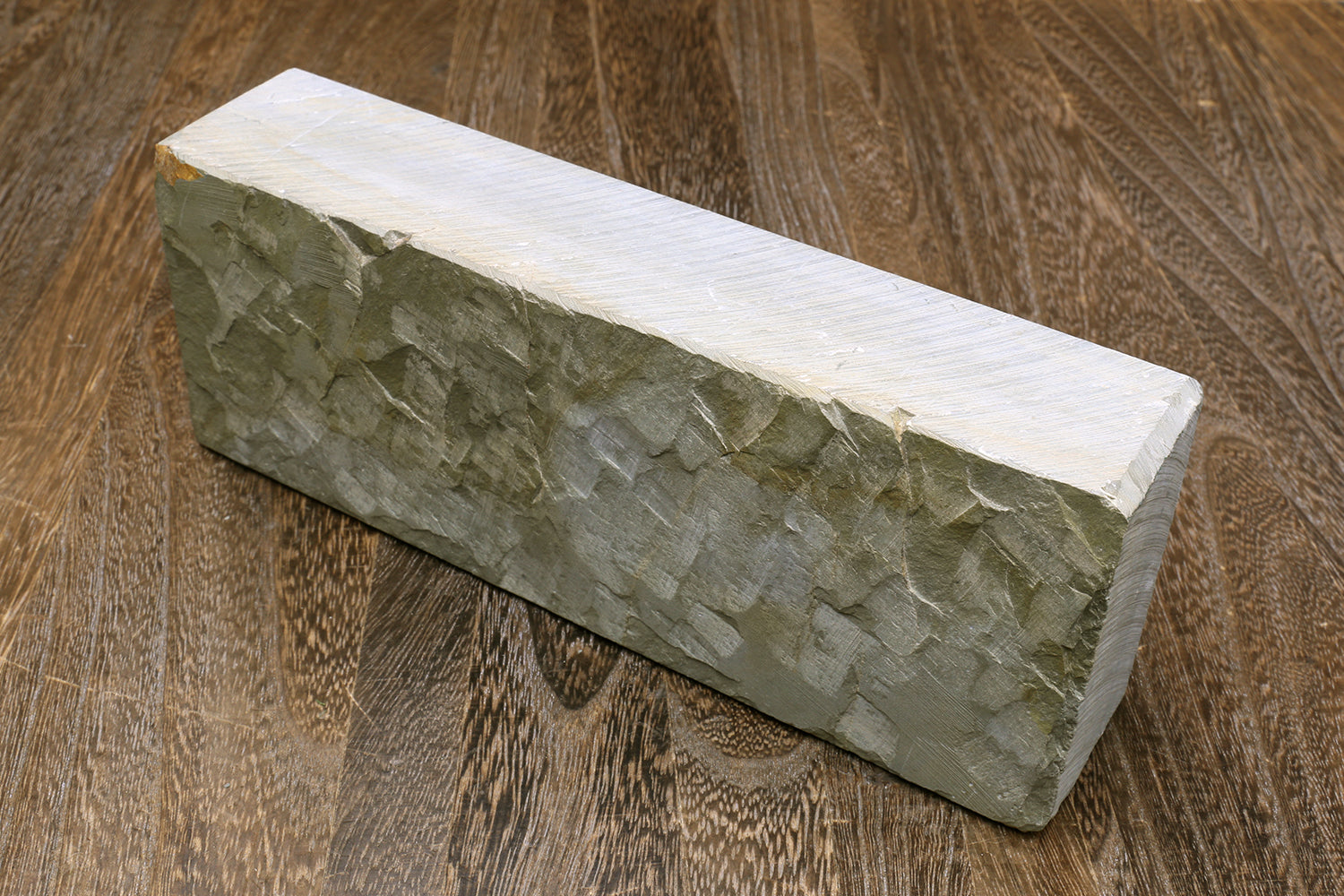 Natural whetstone finishing stone block, green-gray textured side face.