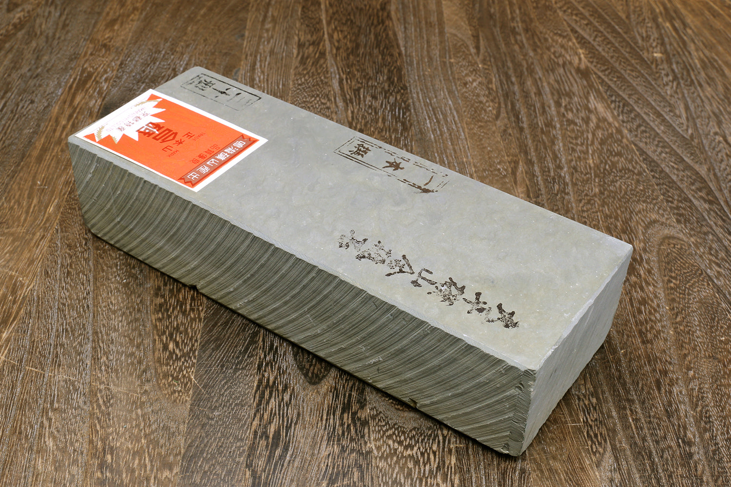 Natural whetstone finishing stone, light gray top with orange label and printed characters.
