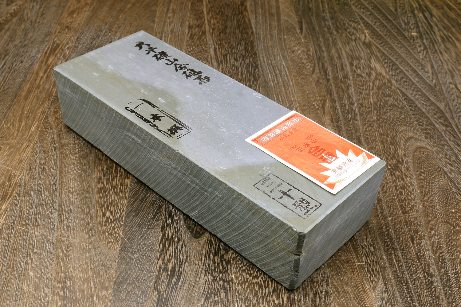 Natural sharpening whetstone block with paper wrapper and orange label