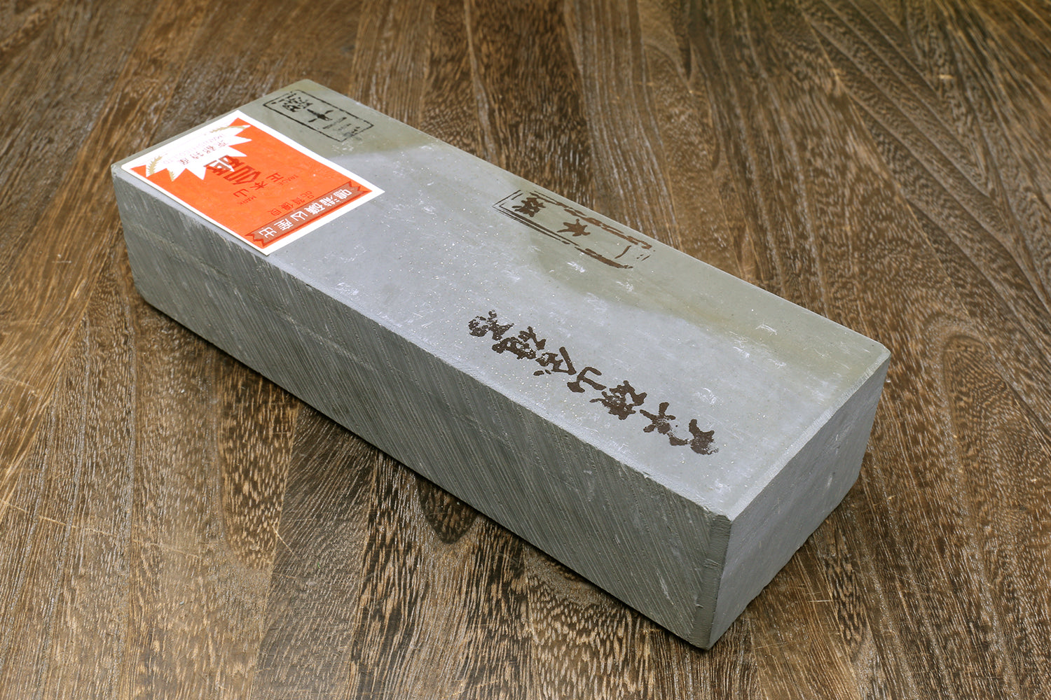 Natural sharpening whetstone block with printed markings and orange label