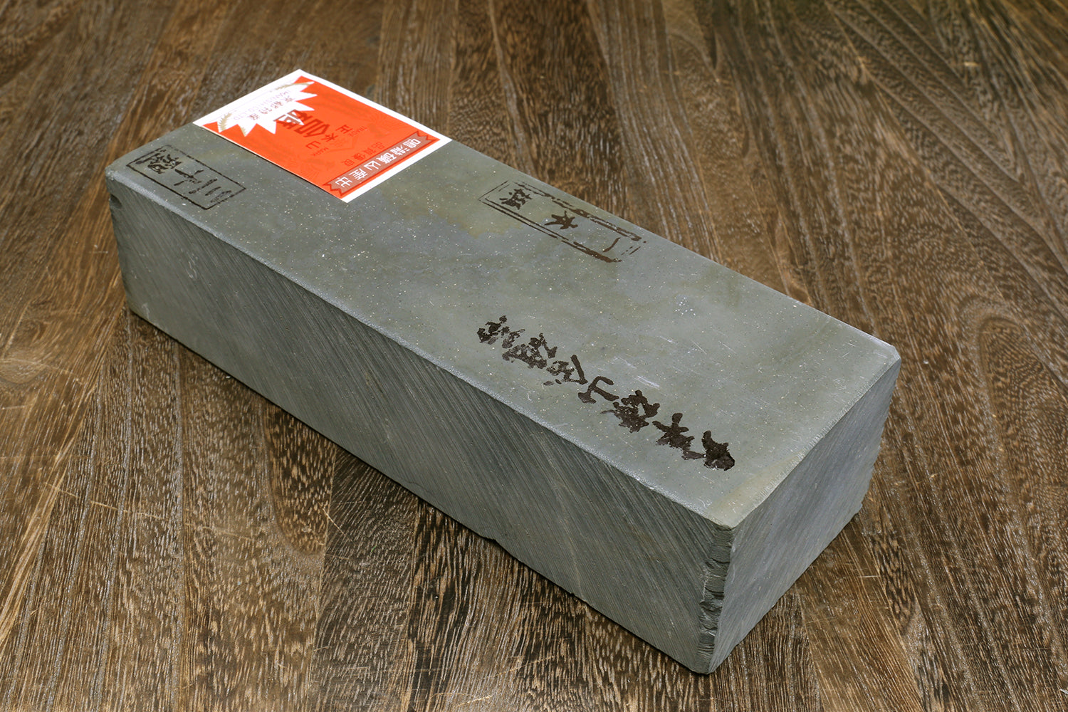 Gray rectangular sharpening whetstone with orange label on top surface
