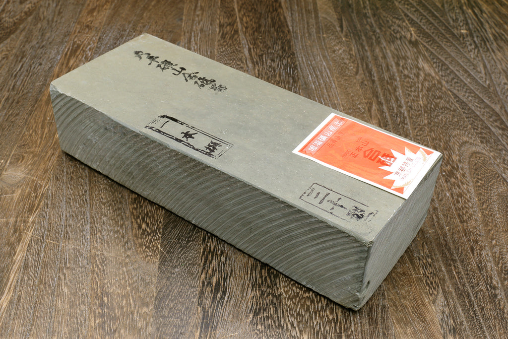 Natural sharpening whetstone block, gray-green rectangle with orange label and markings