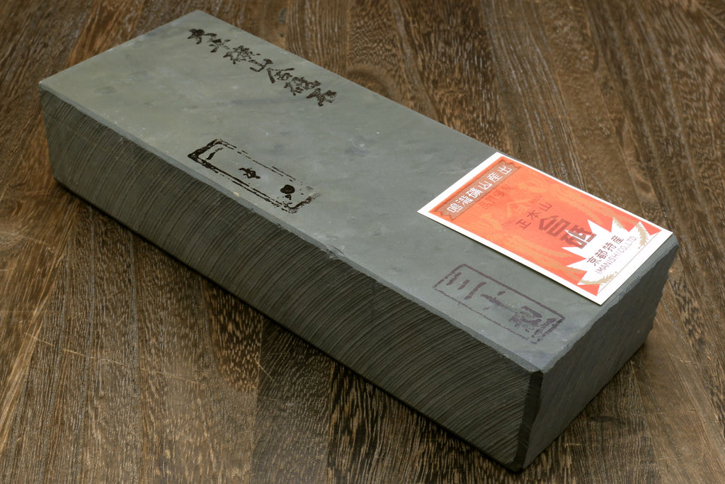 Natural whetstone block with printed label and orange sticker on pale top