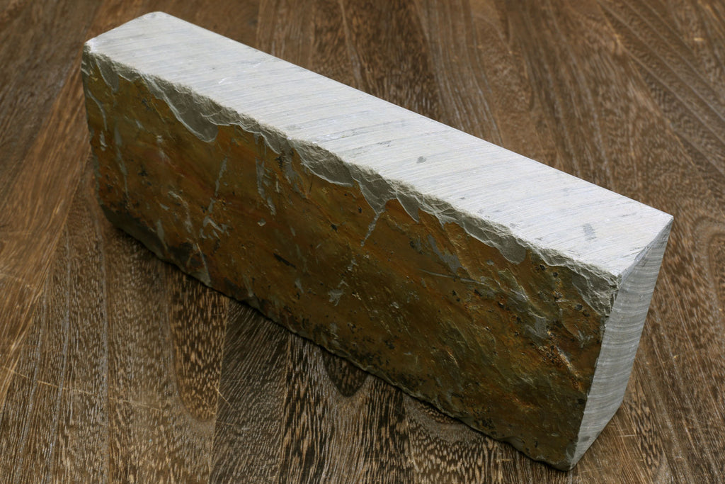 Natural sharpening whetstone, long rectangular block with textured dark side.