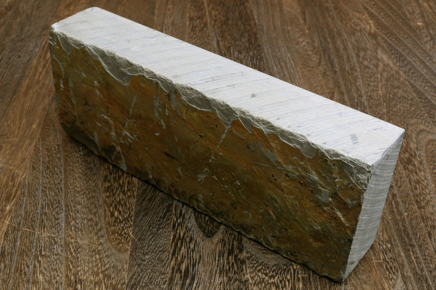 Natural sharpening whetstone, long rectangular block with textured dark side.