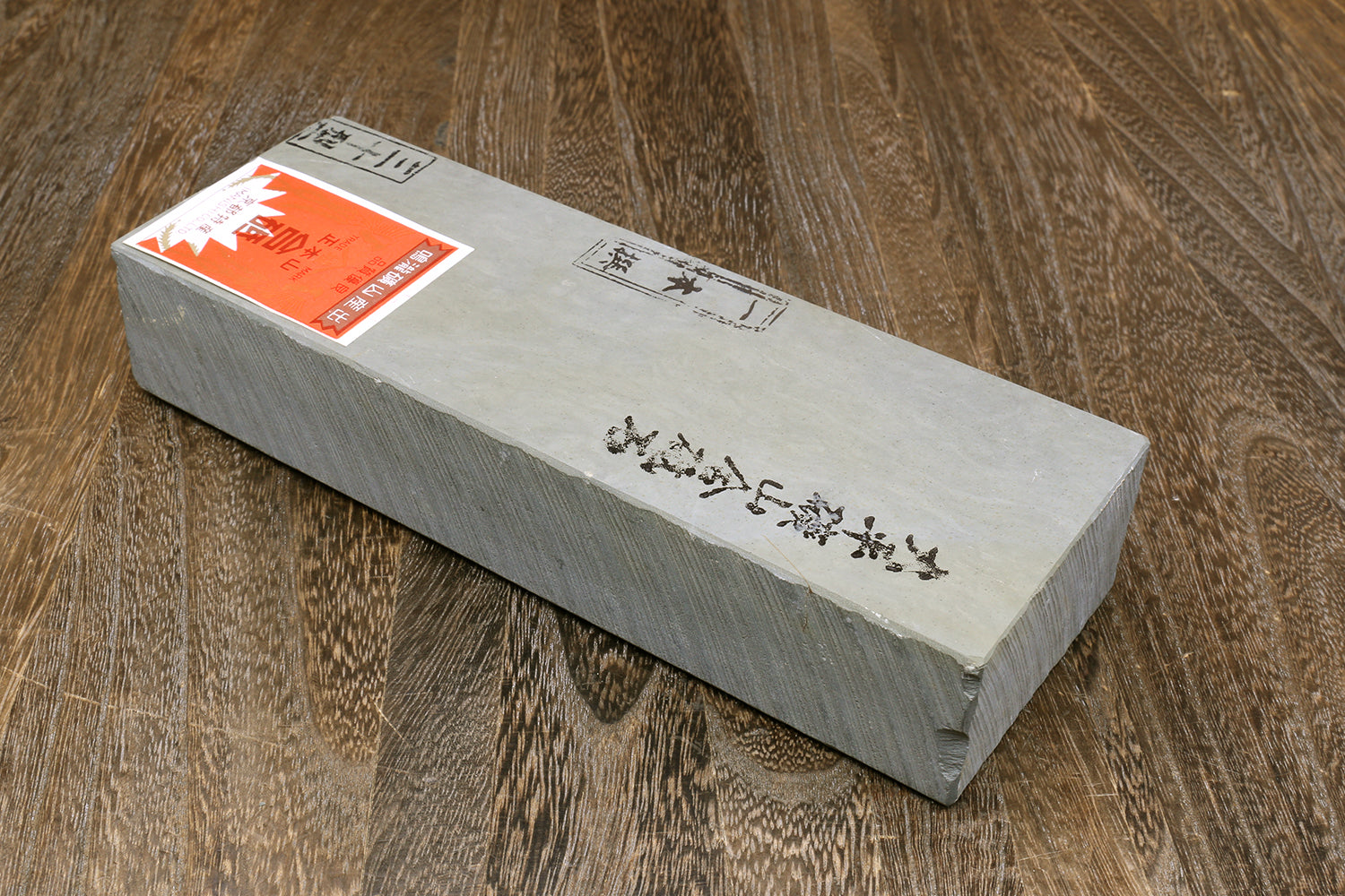 Natural sharpening whetstone with paper labels on top, light gray rectangular block