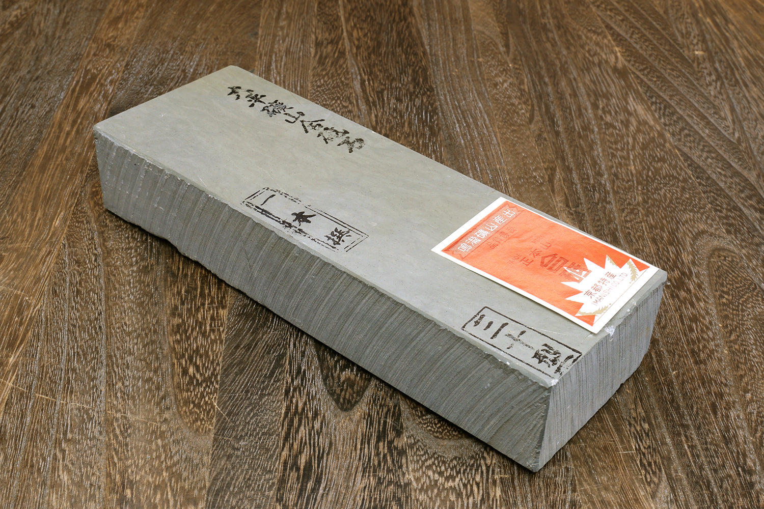 Natural sharpening whetstone with packaging labels on top, light gray block