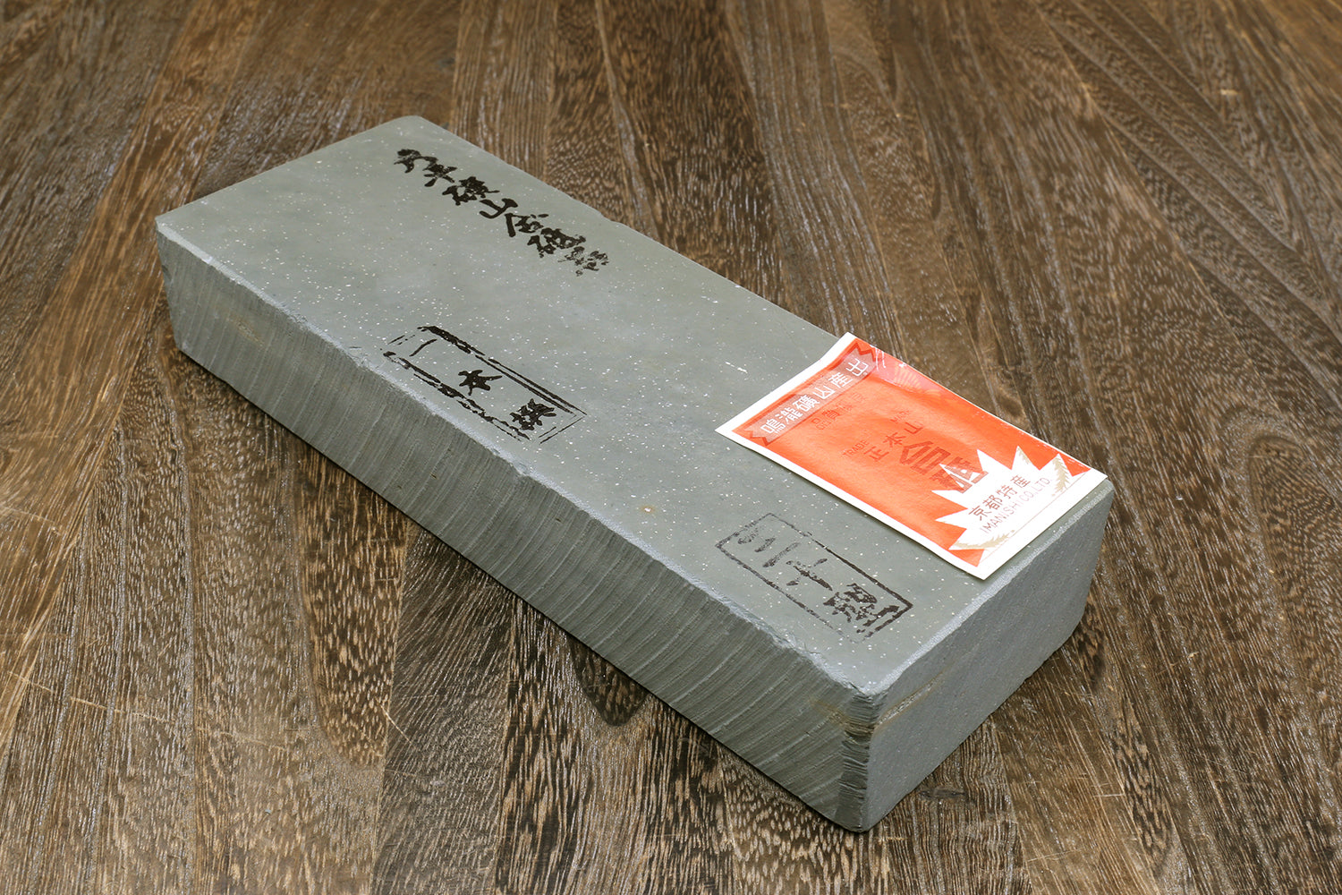 Natural sharpening whetstone with Japanese markings and orange label on one face