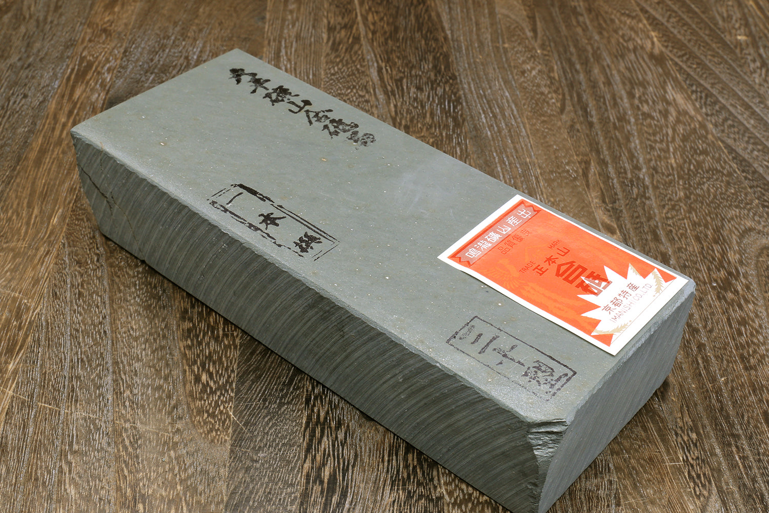 Rectangular grey natural sharpening whetstone with orange sticker on side